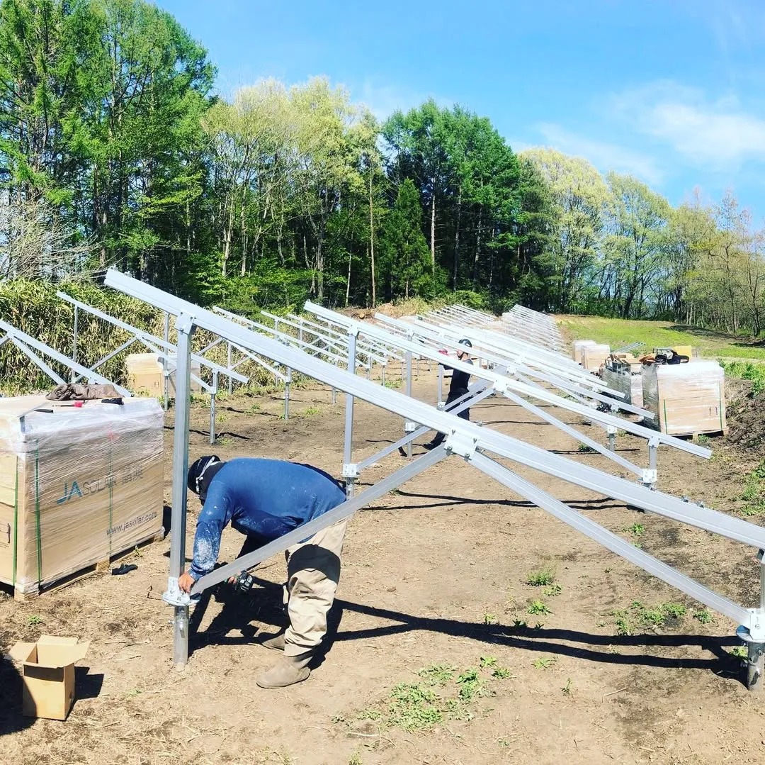 Workers installing ground solar racking and photovoltaic module mounting components